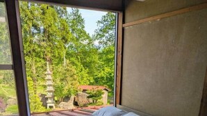 A room with two beds, a large window, and a view of a pagoda.