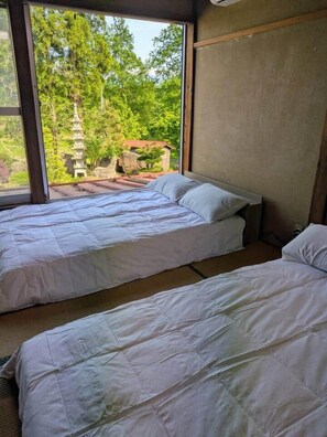 A room with two beds, a large window, and a view of a pagoda.