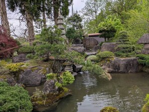 Un jardín tranquilo con un estanque, rocas y construcciones tradicionales japonesas.