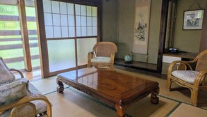 A traditional Japanese room with tatami flooring, a wooden coffee table, and bamboo chairs.