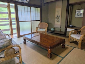 Una habitació tradicional japonesa amb fusta de tatami, una taula de cafè de fusta i cadires de bambú.