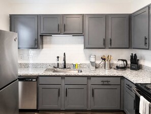 A kitchen with grey cabinets, a stainless steel refrigerator, a coffee maker, and a kettle. - Pet-Friendly 2BR Dallas Retreat - Sleeps 6 (Dallas)