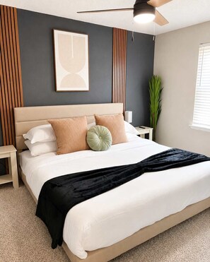 Ein Schlafzimmer mit einem Bett, einem Deckenventilator, einem gerahmten Bild und einem Blumentopf.