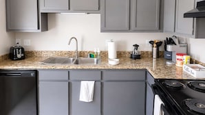A kitchen with grey cabinets, a stainless steel sink, a toaster, a coffee maker, and a stove. - 2BR Dallas Townhome - Pool, King Bed & Parking (Dallas)
