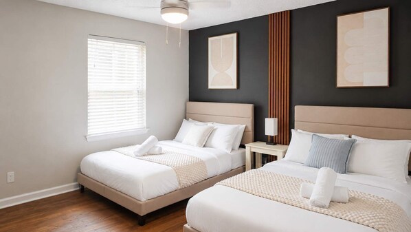 A hotel room with two beds, a nightstand, a lamp, and artwork on the walls. - 2BR Near Medical District - Pool & Parking (Dallas)