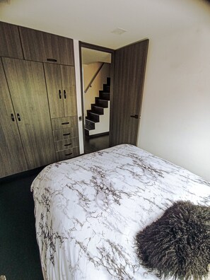 Een slaapkamer met een bed, een kledingkast en een trap.