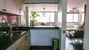 Ett modernt kök med en central köksö, rostfria vitvaror och utsikt över vardagsrummet.