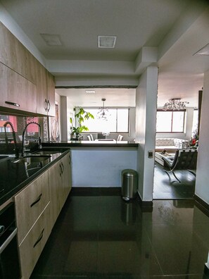 Een moderne keuken met een centraal eiland, roestvrijstalen apparatuur en uitzicht op de woonkamer.