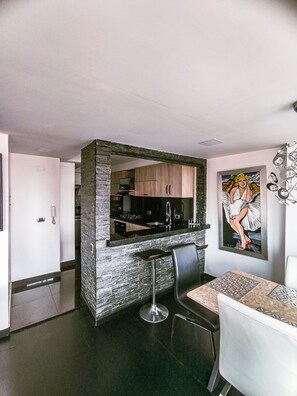 A modern kitchen with a built-in island, a dining area with a bar stool, and a framed artwork on the wall. - Beautiful and Spacious Apartment in Chapinero Bogota DC (Bogotá, D.C.)