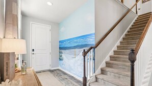 Un escalier avec des rampes en bois et un sol recouvert d’une moquette beige, menant à une porte.