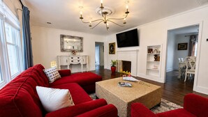 A living room with a red sofa, a coffee table, a fireplace, and a TV mounted on the wall.