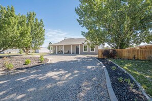 A residential house with a gravel driveway, a wooden fence, and a well-maintained lawn. - NEW! Horsethief Hideaway Near Trails (Loma)