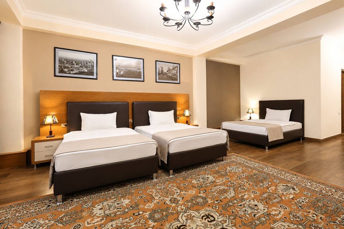 Habitación de hotel con dos camas, una araña y un tapete estampado.