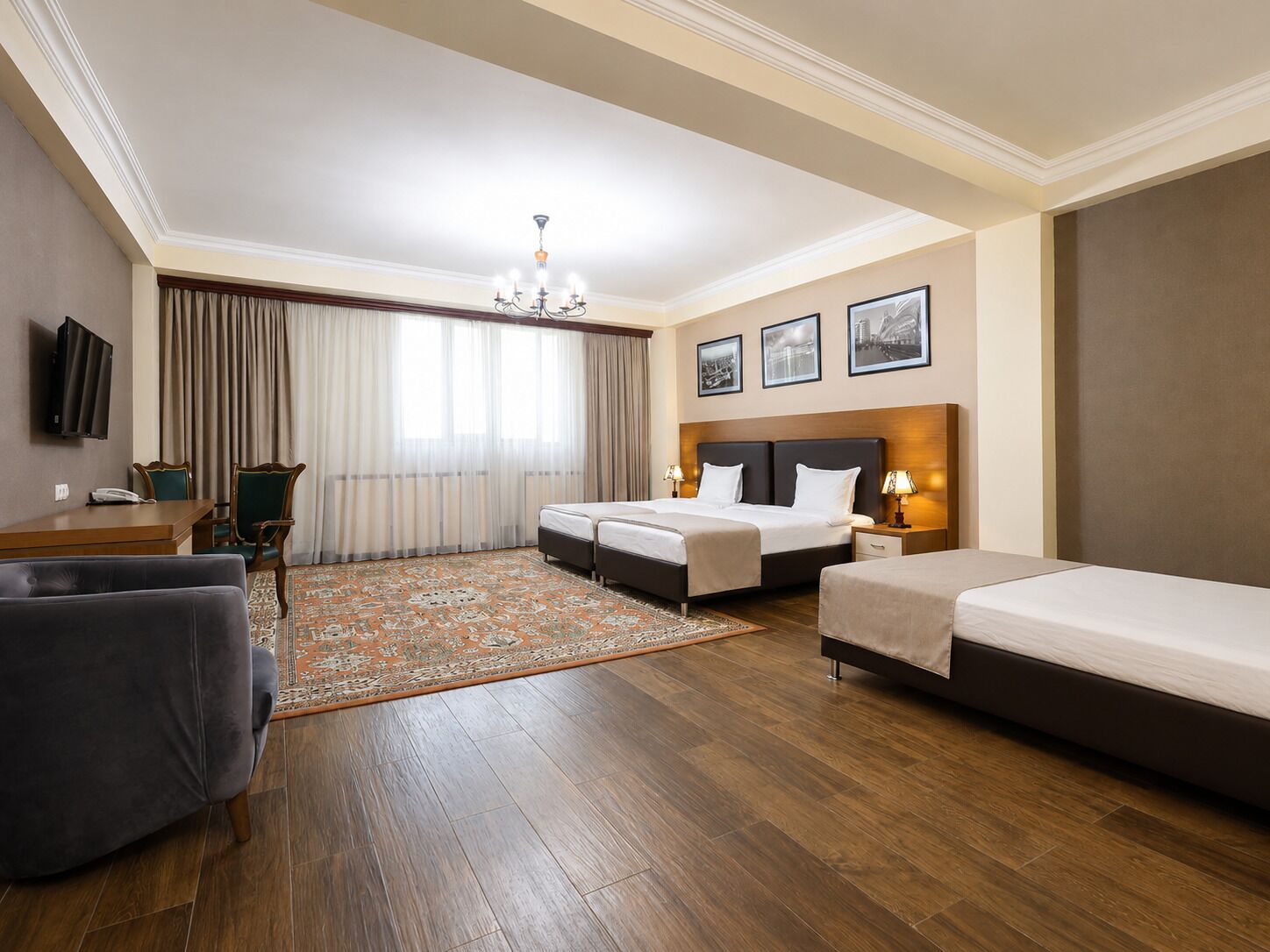 Une chambre d’hôtel avec un lit, un bureau, une chaise, une télévision et un lustre.