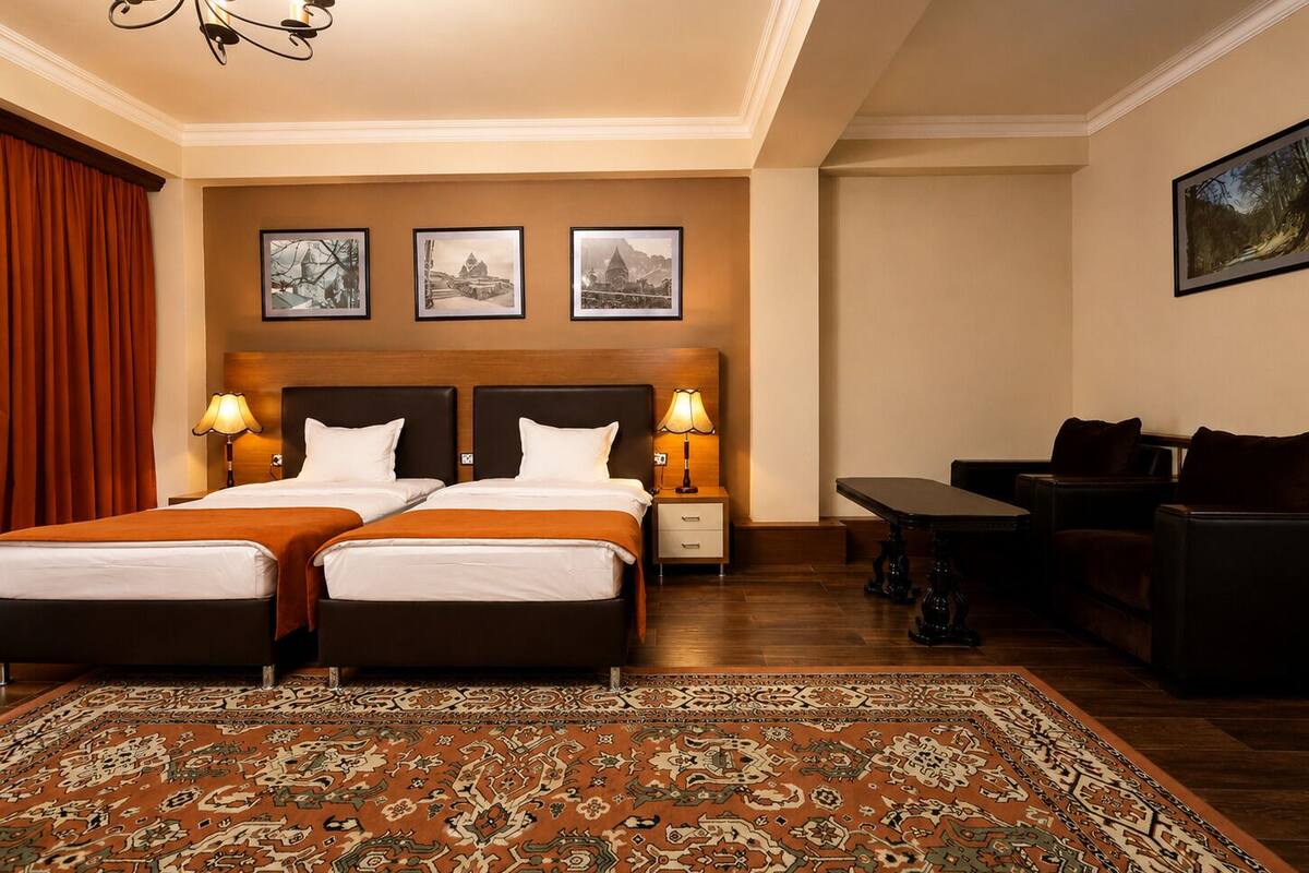 Habitación de hotel con dos camas, un sofá, una mesa y una araña.