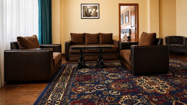 Ein Wohnzimmer mit einer Couch, Sesseln, einem Couchtisch und einem gemusterten Teppich.