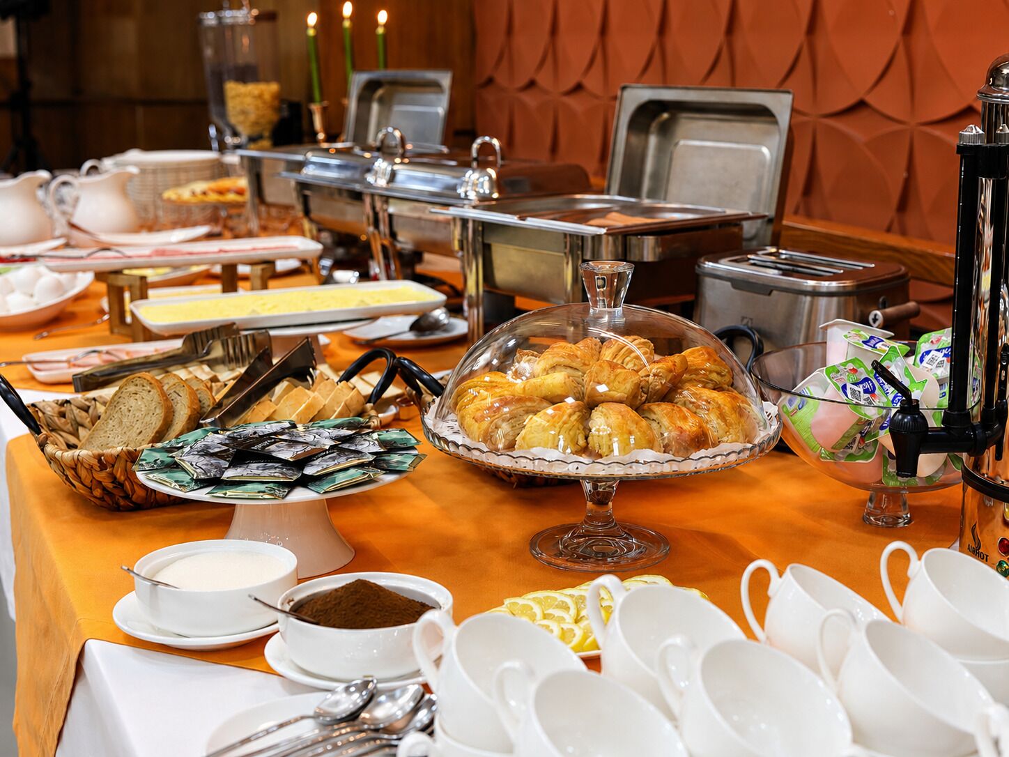 A buffet setup with various food items, including pastries, bread, and beverages.