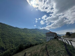 Ein Gebäude mit rotem Dach, umgeben von saftig grünen Hügeln und blauem Himmel.