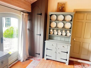 A room with a sliding glass door, a white cabinet with plates, and a wooden door. - THE COACH HOUSE COTTAGE, pet friendly, with open fire in Ballycommon (NENAGH)