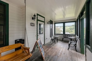 A wooden porch with a bench, a table with chairs, and a signboard. - Victorian House | Unit 454 | 1 Queen Bed (Elkhart Lake)