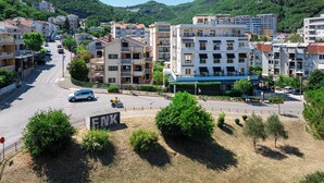 Ein mehrstöckiges Hotel mit Balkonen, einem Parkplatz und Blick auf eine hügelige Landschaft.