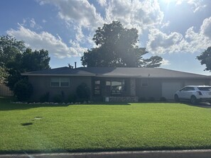 A single-story house with a garage, a well-maintained lawn, and a parked white car. - FULLY FURNISHED 4 bed 3 bath, bills paid, internet, washer/dryer, maid service (Vernon)