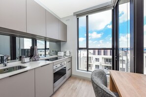 Moderni keittiö, jossa on suuri ikkuna, ruokailutila ja näkymä rakennuksiin.