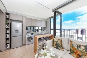 Eine moderne Küche mit integriertem Waschmaschine, ein Essbereich mit Holztisch und Stühlen sowie ein Balkon mit Blick auf die Stadt.