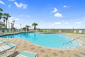 A swimming pool with lounge chairs, palm trees, and a view of the ocean. - Golden Aura | Pool Front | Gulf View | Sleeps 6 (Miramar Beach)