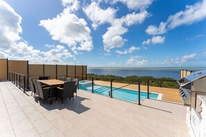 Eine Dachterrasse mit Pool, Gartenmöbeln und Meerblick.