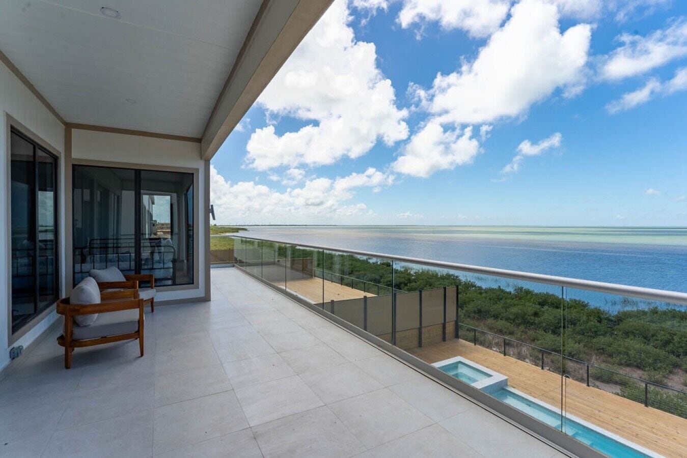 Un balcón con vistas al mar, una piscina y una zona de estar.