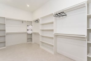 A walk-in closet with multiple shelves and hanging space, a tiled floor, and a white interior. - 4,000 SF Waterfront Home w/ Pool, Sleeps 22 (Port Isabel)