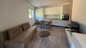 Ett modernt kök med vita skåp, en väggbeklädnad av marmor och en matplats med bord och stolar.
