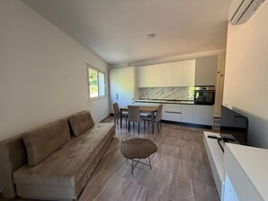 Eine moderne Küche mit weißen Schränken, einer Marmor-Spritzschutzwand und einem Essbereich mit Tisch und Stühlen.