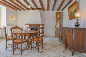 A dining area with a wooden table and chairs, a clock, and a cabinet.