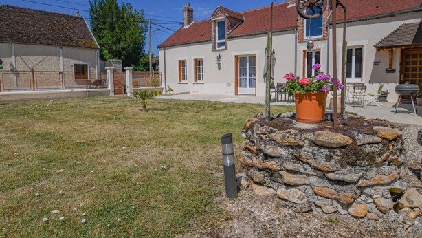 A residential area with houses, a stone wall, and a metal sculpture.
