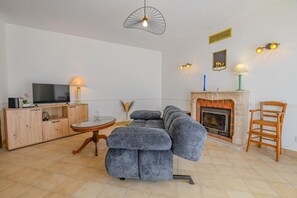 Ein Wohnzimmer mit Sofa, Fernseher, Kamin und einer Pendelleuchte.
