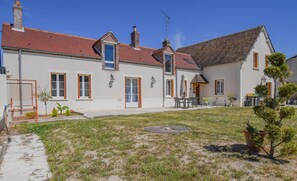 A two-story house with a red-tiled roof, a small garden, and a patio area with outdoor furniture. - Vacation Rental in the Seine Valley (LA MOTTE TILLY)