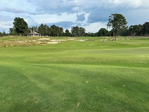 Un campo da golf con bunker di sabbia, un padiglione e un gruppo di persone.