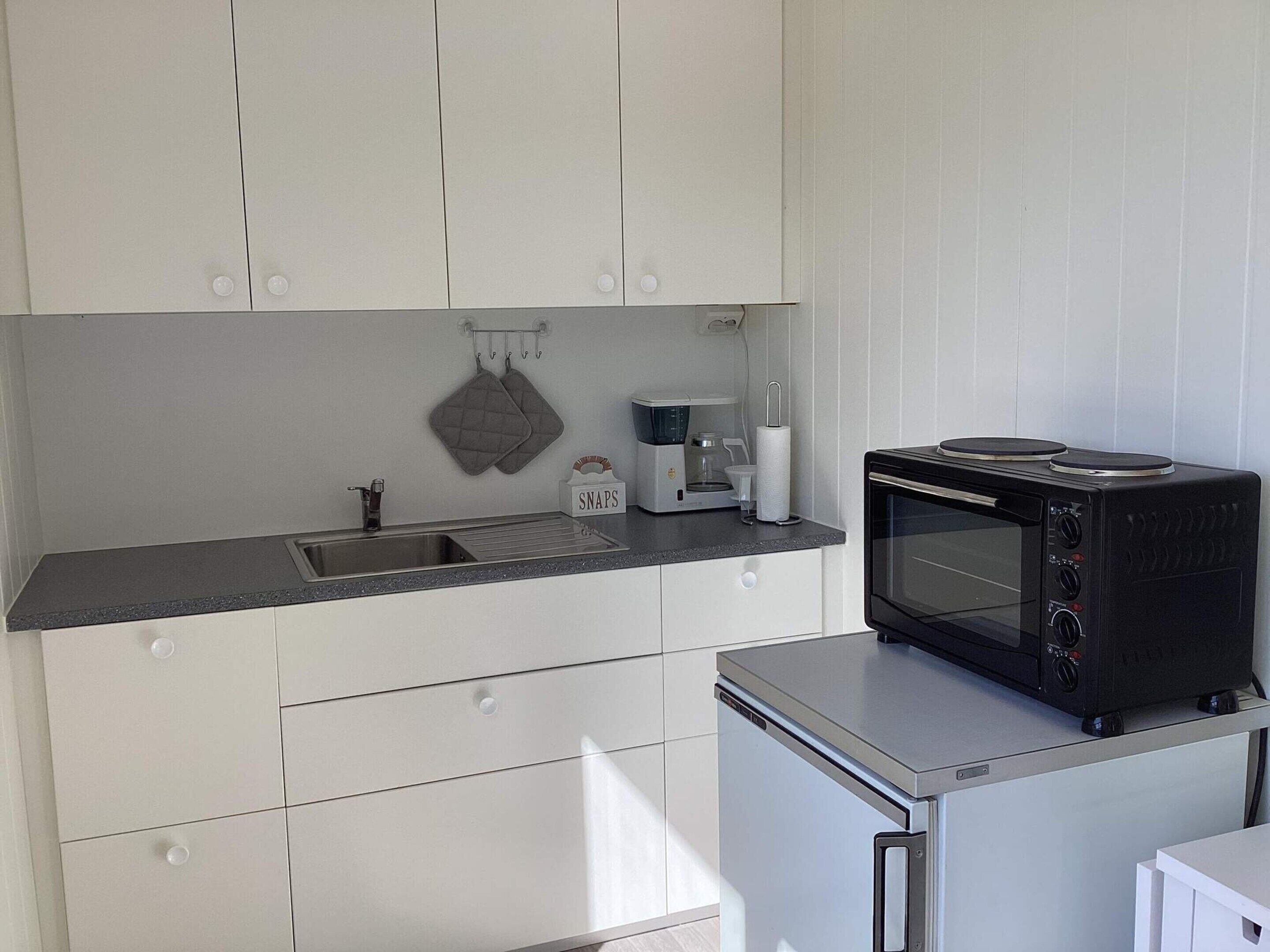 Una cocina compacta equipada con microondas, cafetera y hervidor.