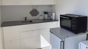 A compact kitchen with a built-in microwave, a coffee maker, and a kettle. - 4 Person Holiday Home in Stromstad (Stromstad)