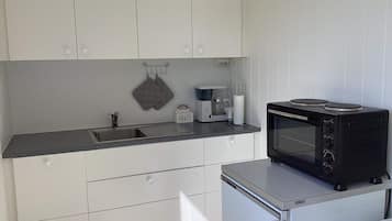 Una cocina compacta equipada con microondas, cafetera y hervidor.