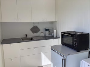 Una cocina compacta equipada con microondas, cafetera y hervidor.