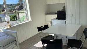 A compact kitchen with a dining area, a window with a view of a lake, and a small refrigerator. - 4 Person Holiday Home in Stromstad (Stromstad)