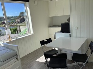 A compact kitchen with a dining area, a window with a view of a lake, and a small refrigerator. - 4 Person Holiday Home in Stromstad (Stromstad)