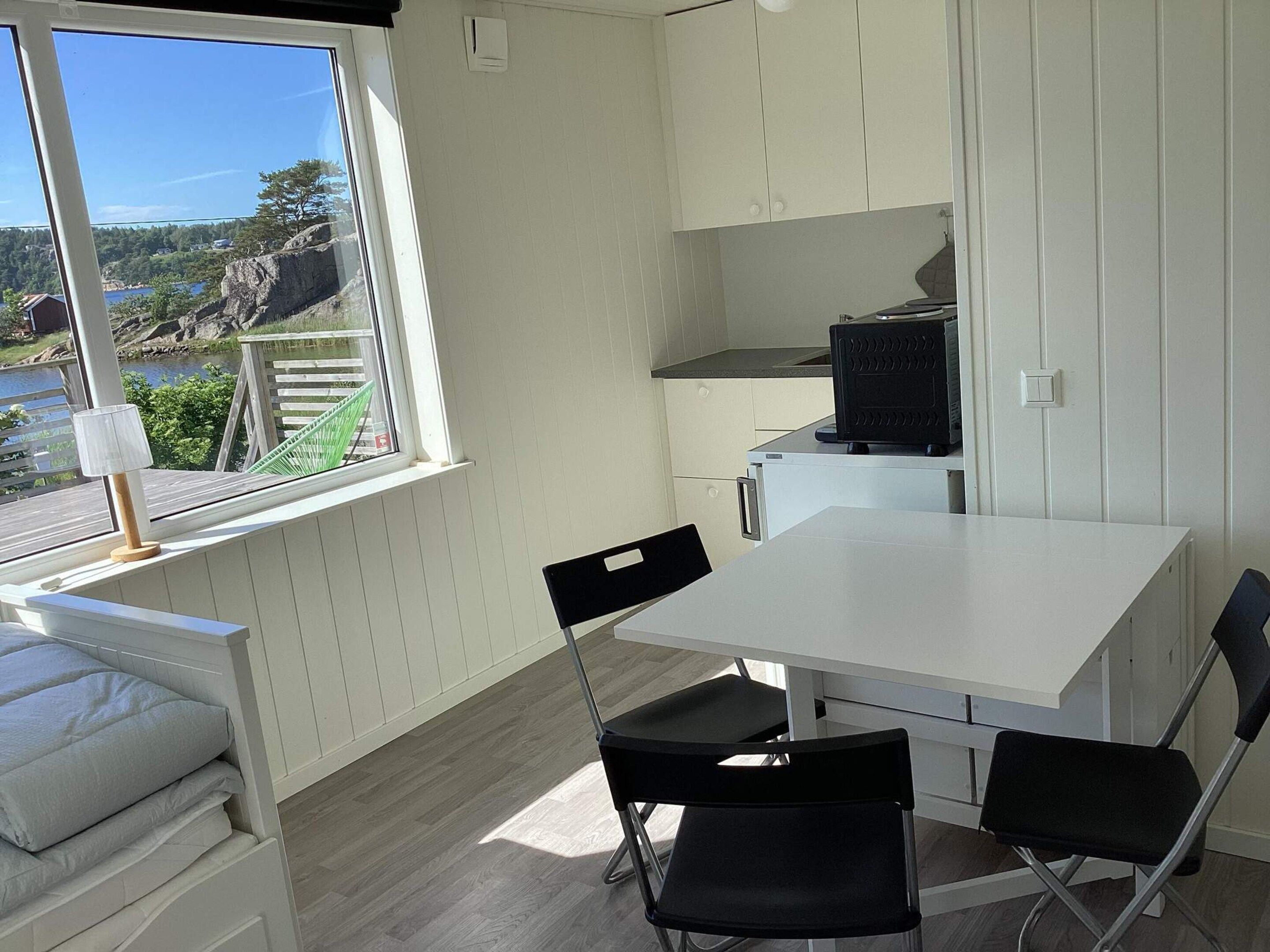 A compact kitchen with a dining area, a window with a view of a lake and trees, and a built-in microwave.