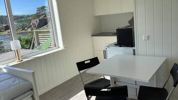 A compact kitchen with a dining area, a window with a view of a lake and trees, and a built-in microwave.