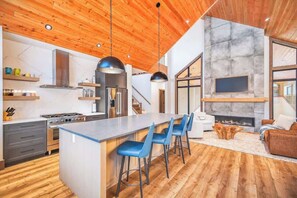 A modern kitchen with a central island, bar stools, and a fireplace.
