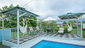 A pool area with a tiled deck, lounge chairs, and a hammock. - Gato&Culla House (La Fortuna)