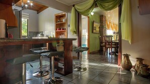 A kitchen with a bar area, bar stools, and a dining area with chairs. - Gato&Culla House (La Fortuna)